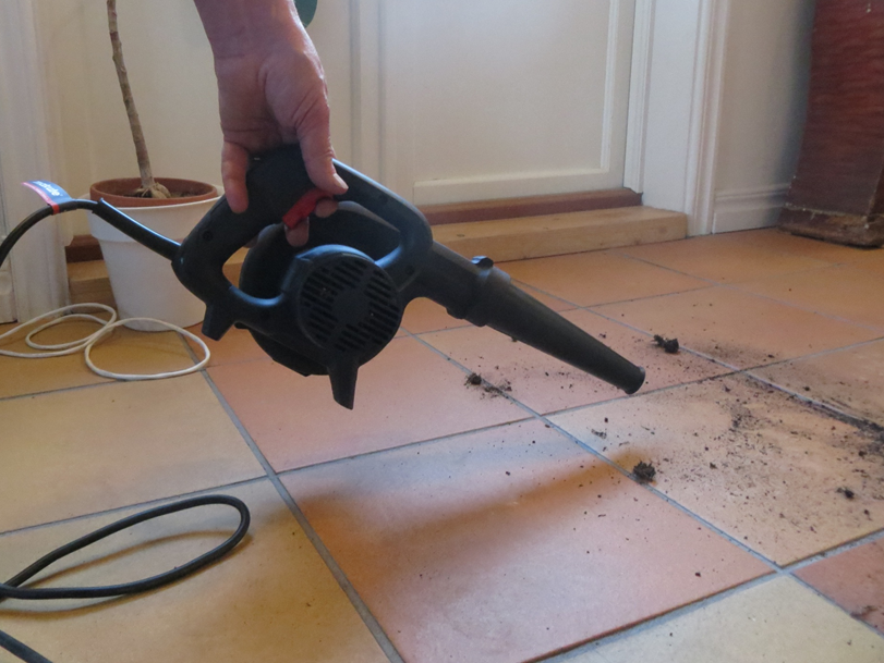 Using an air blower to remove dirt and debris on floor tiles